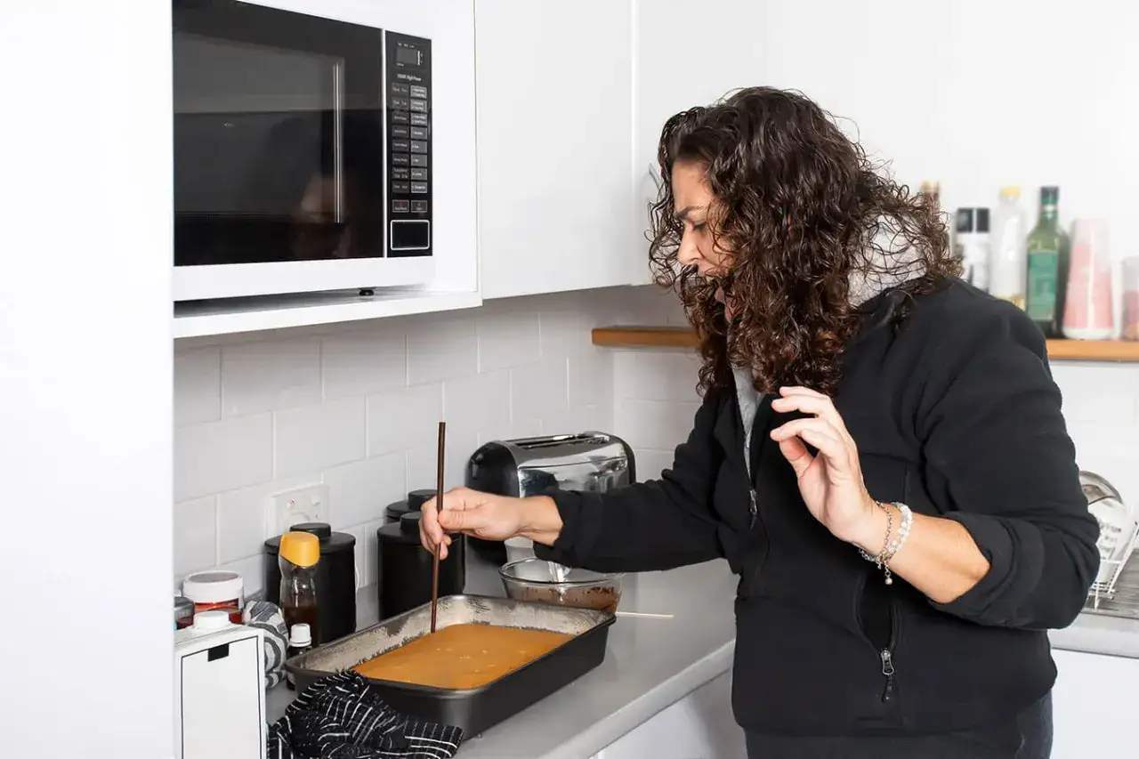 Kobieta sprawdza patyczkiem upieczony pasztet w formie.