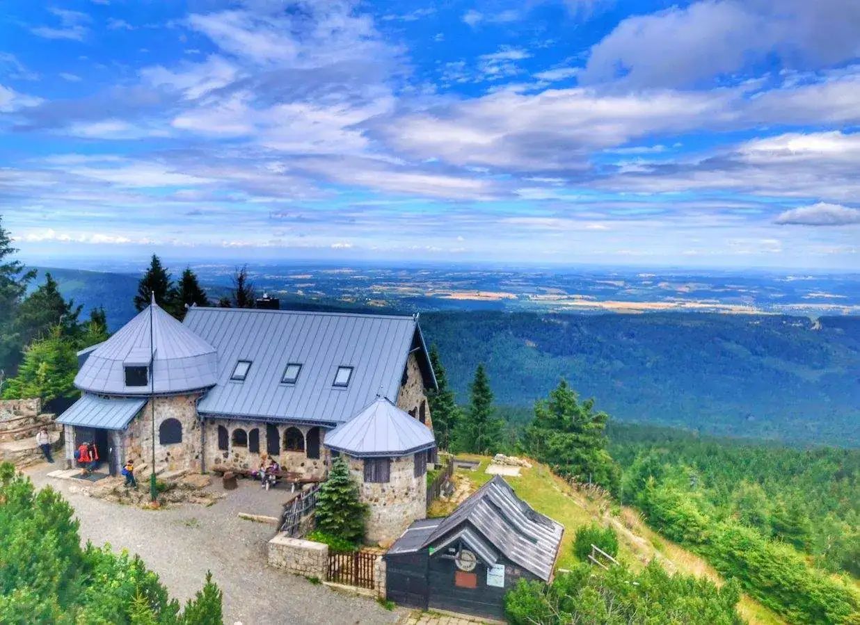 Kamienny schronisko na szczycie góry, z którego roztacza się piękny widok. Idealne miejsce na odpoczynek po wędrówce, zastanawiając się, jakie szlaki w Szklarskiej Porębie wybrać.