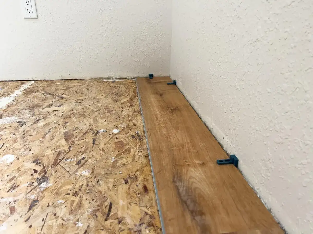 Układanie paneli winylowych na płycie OSB. Wylewka nie jest widoczna, ale panele są już częściowo ułożone.