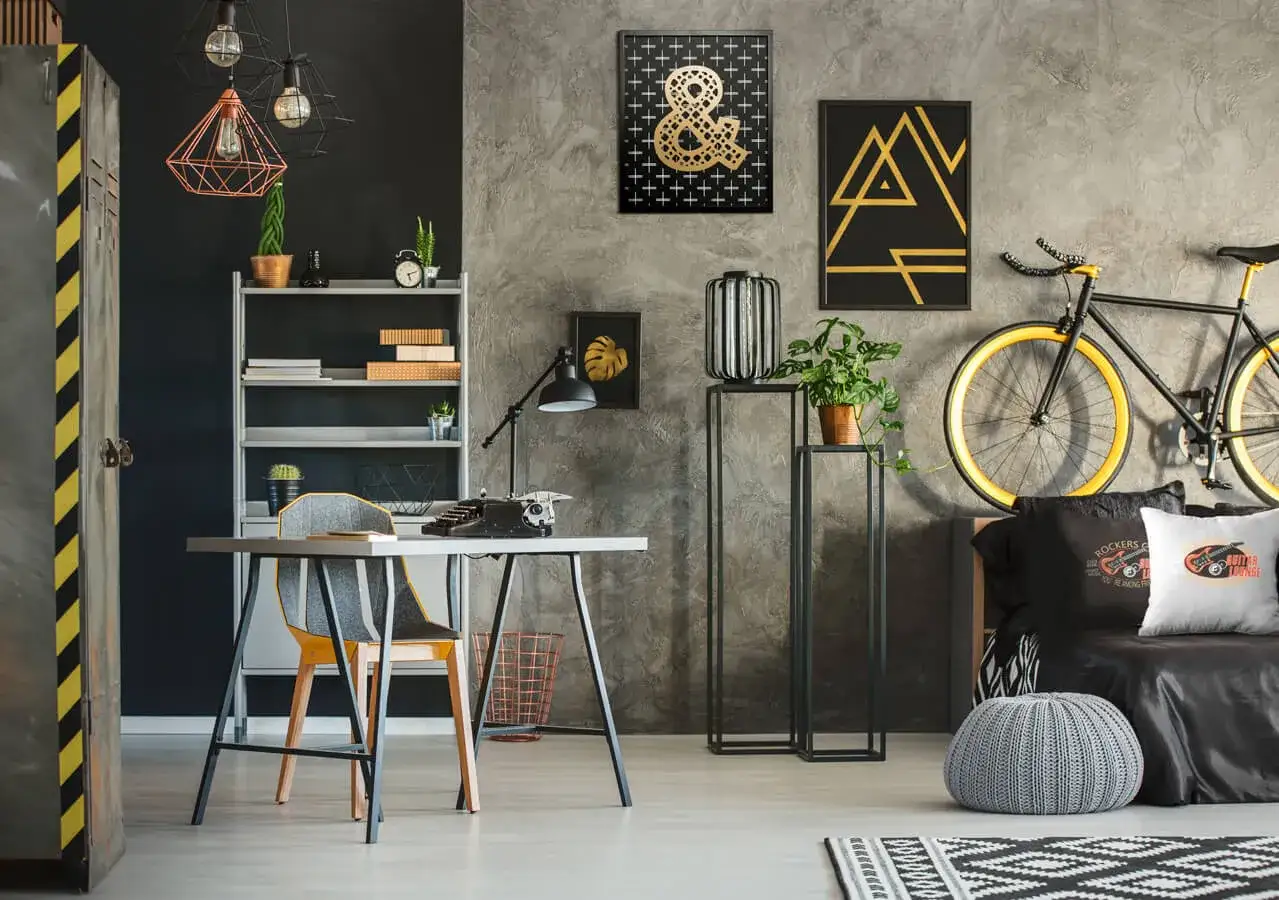 Nowoczesne ściany w pokoju młodzieżowym z betonową fakturą, ozdobione złotymi grafikami i czarnymi akcentami. Styl industrialny i rockowy.