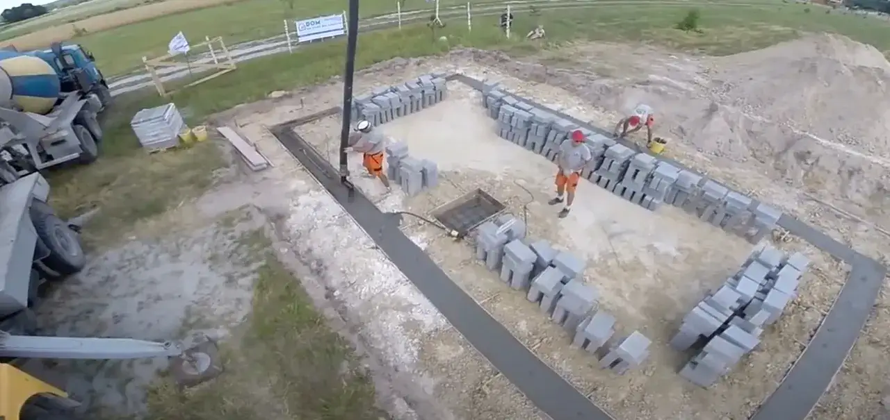 Budowa fundamentów: betonowanie i układanie bloczków przez robotników.