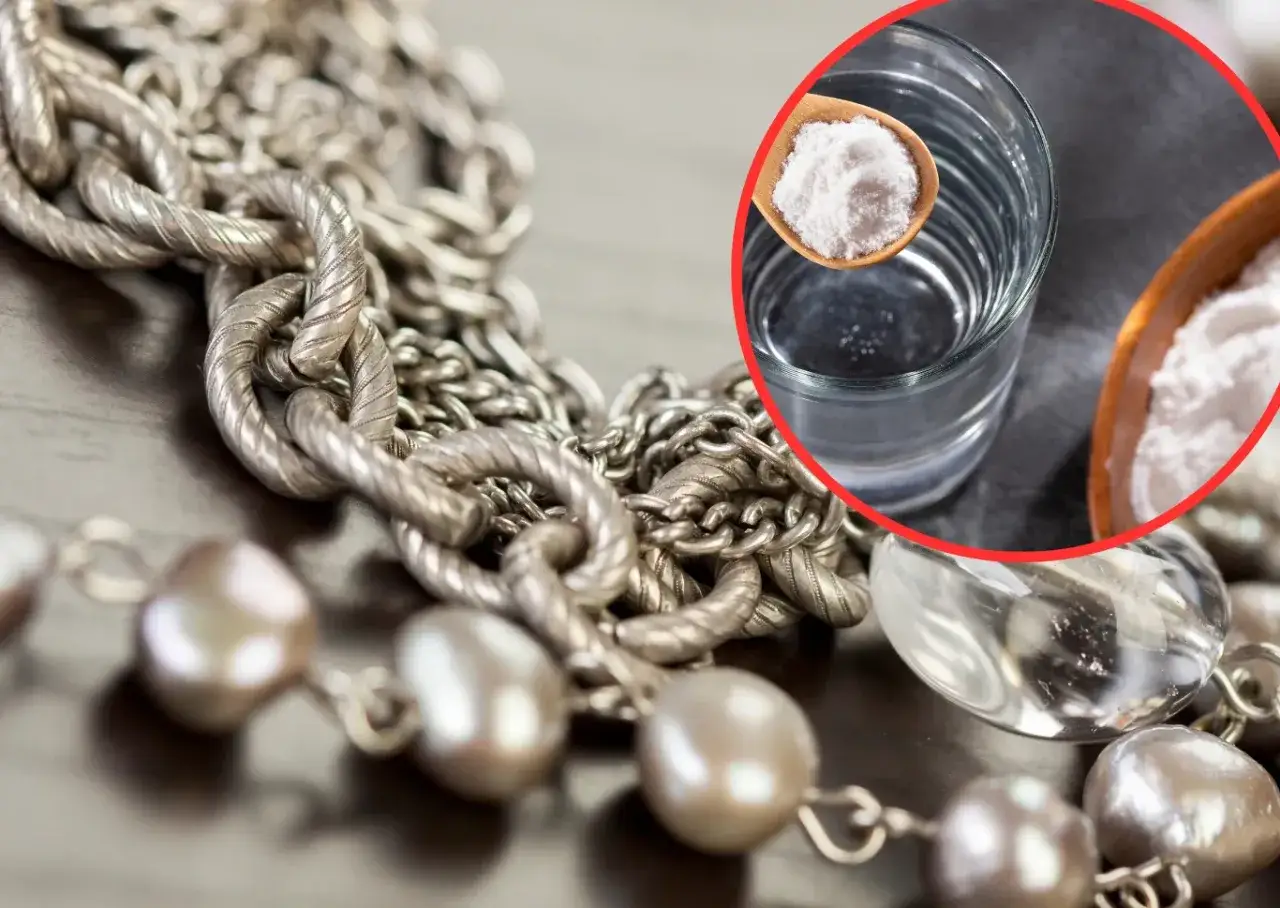 Srebrny naszyjnik i łyżka z sodą oczyszczoną obok szklanki wody.