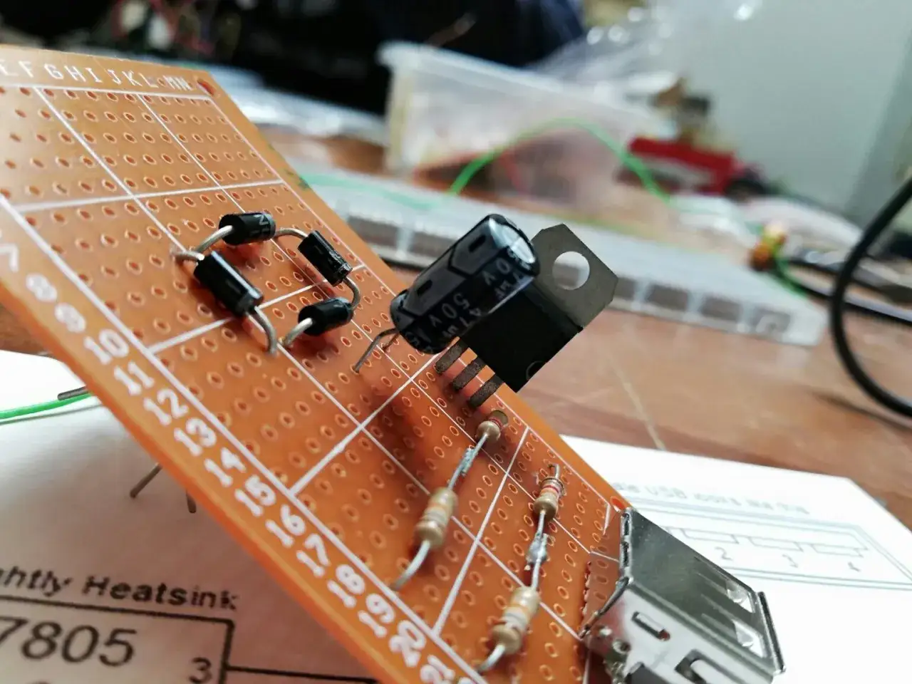 Układ elektroniczny na płytce stykowej z diodami, rezystorami i kondensatorem. Widać też element przypominający warystor.