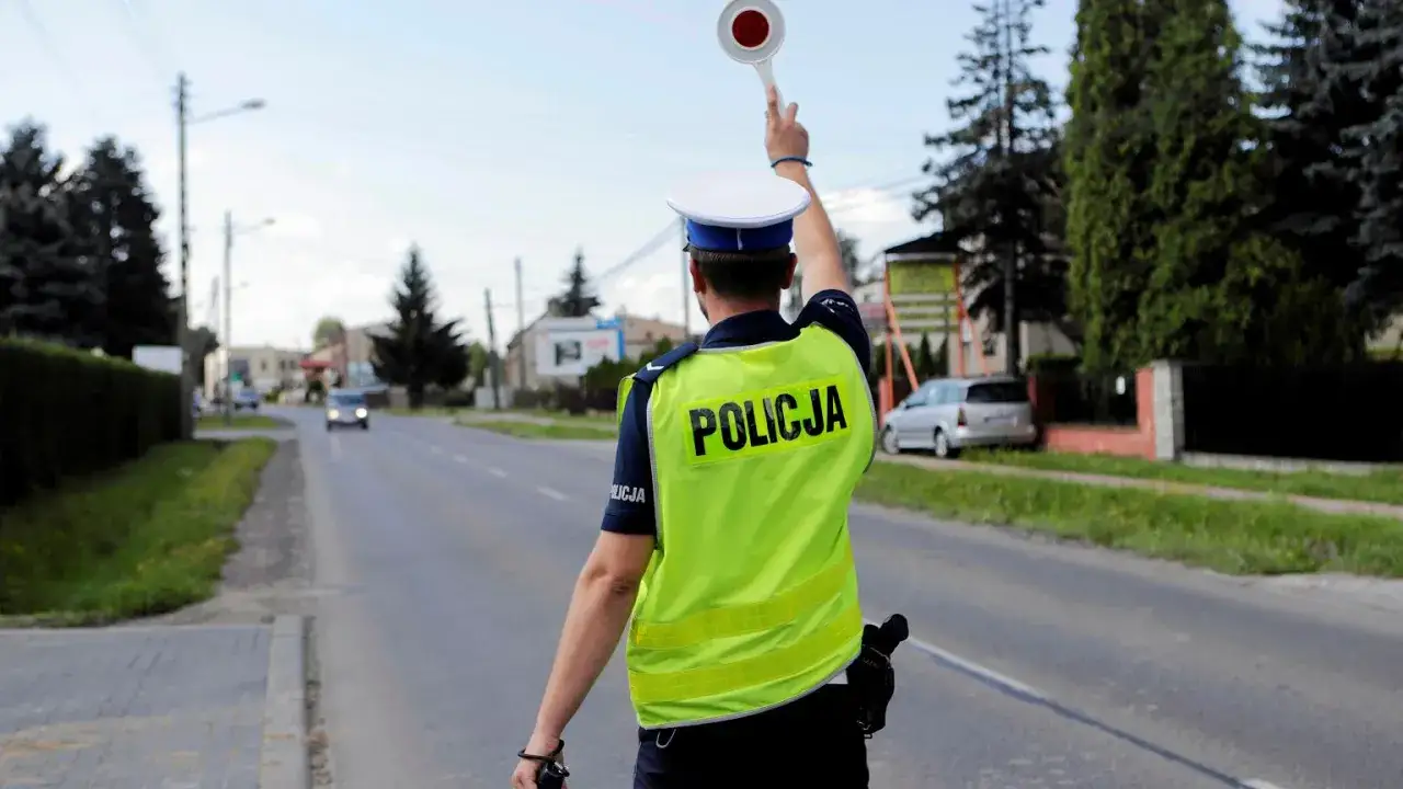 Policjant zatrzymuje ruch, by ukarać kierowcę za przekroczenie prędkości o 30 w terenie zabudowanym.