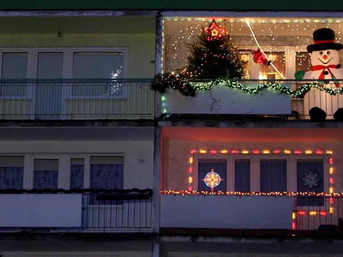 Świąteczne dekoracje na balkonach: choinka, bałwan, Mikołaj i lampki. Pomysł, jak zawiesić lampki na balkonie, by stworzyć magiczny klimat.