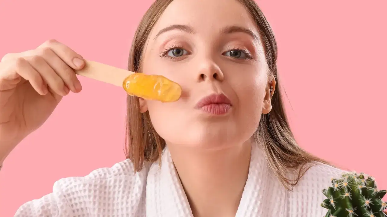 Młoda kobieta z woskiem do depilacji na patyczku, gotowa usunąć meszek na twarzy.