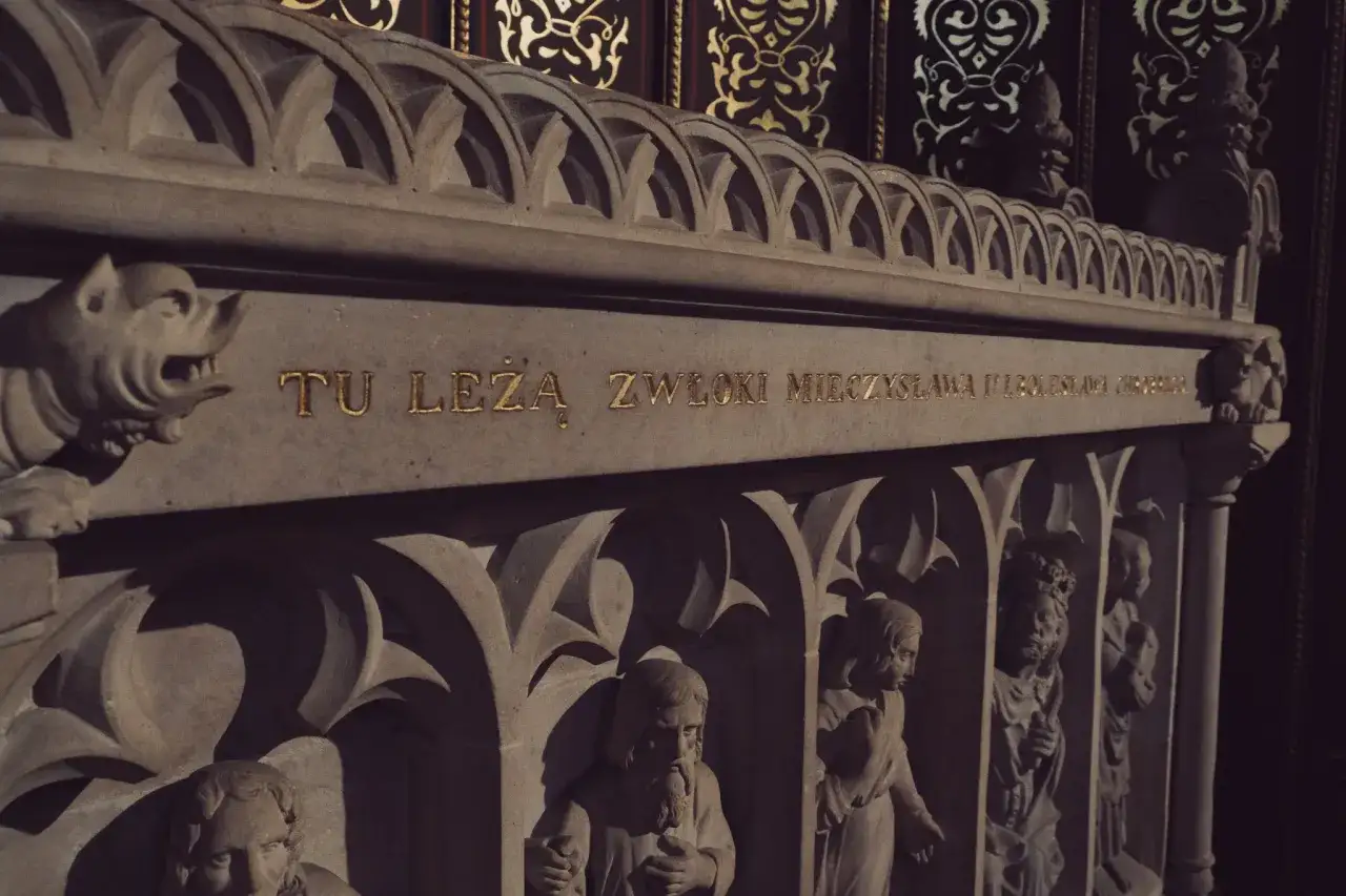 Kamienny sarkofag z napisem "TU LEŻĄ ZWŁOKI MIECZYSŁAWA II" i płaskorzeźbami postaci. Jutrznia za zmarłego.
