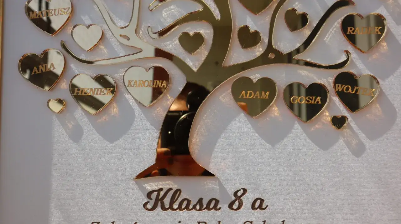 Złote serca z imionami uczniów na tle drzewa, pod napisem "Klasa 8 a".