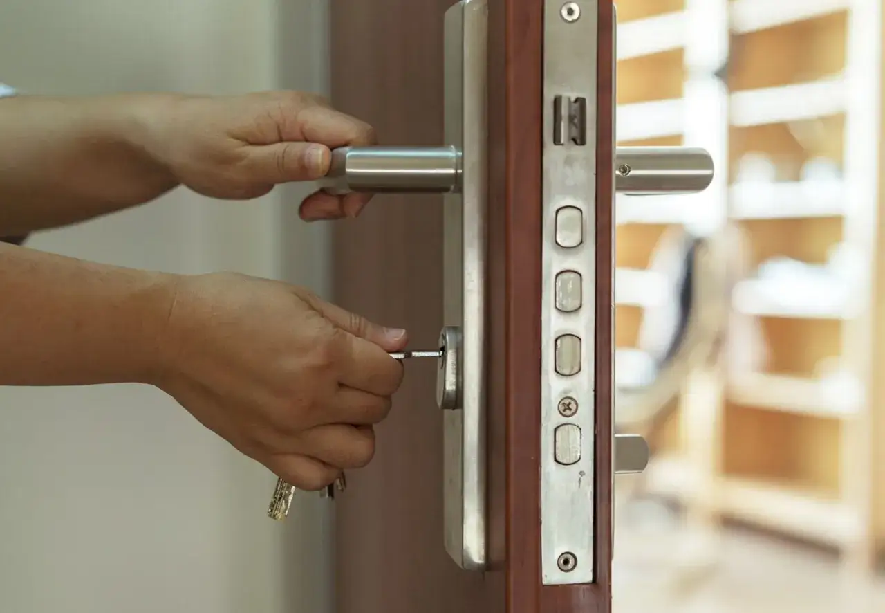Dłonie wkładają klucz do zamka w drzwiach antywłamaniowych. Zapewniają bezpieczeństwo i spokój.