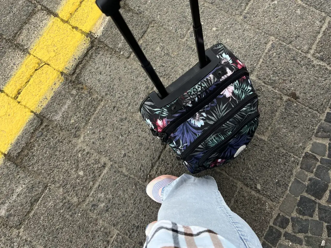 Podróżujesz z Ryanair? Jaki bagaż w cenie biletu? Mała, kwiecista walizka na kółkach czeka na lot.