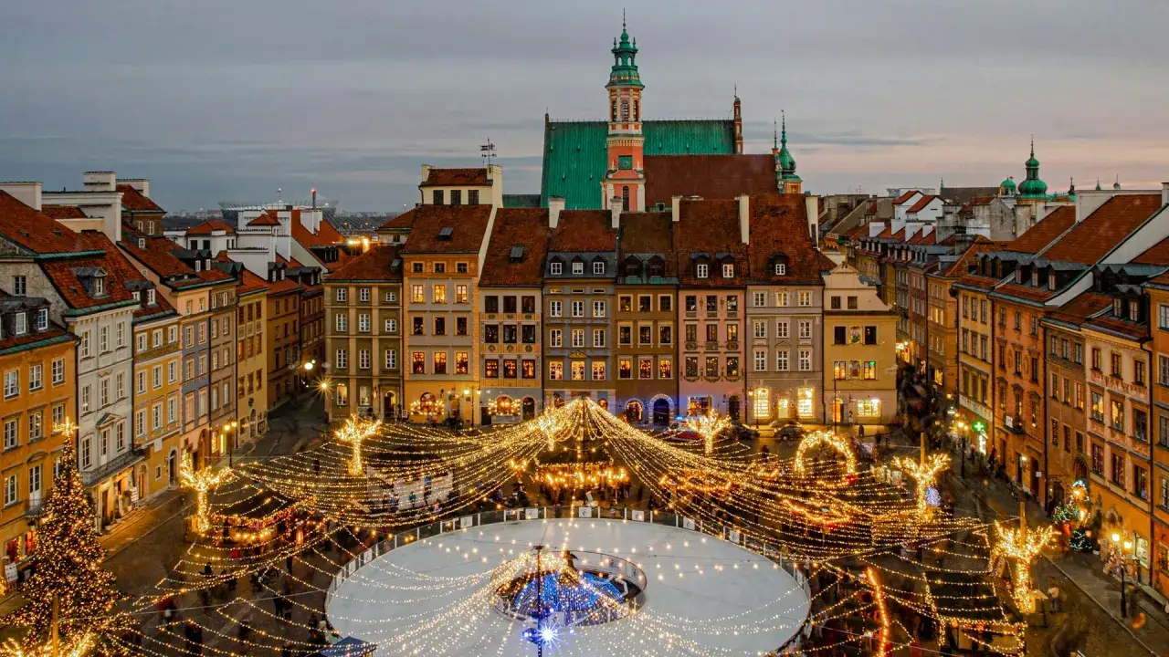 Magiczny zimowy wieczór w Warszawie. Rynek Starego Miasta rozświetlony tysiącami lampek, lodowisko i choinka tworzą idealny klimat na city break w Polsce.