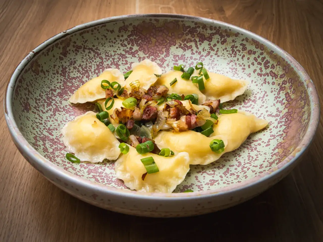 Pyszne pierogi z boczkiem i cebulką, ozdobione szczypiorkiem. Pozycja z menu bacówki Jamna.