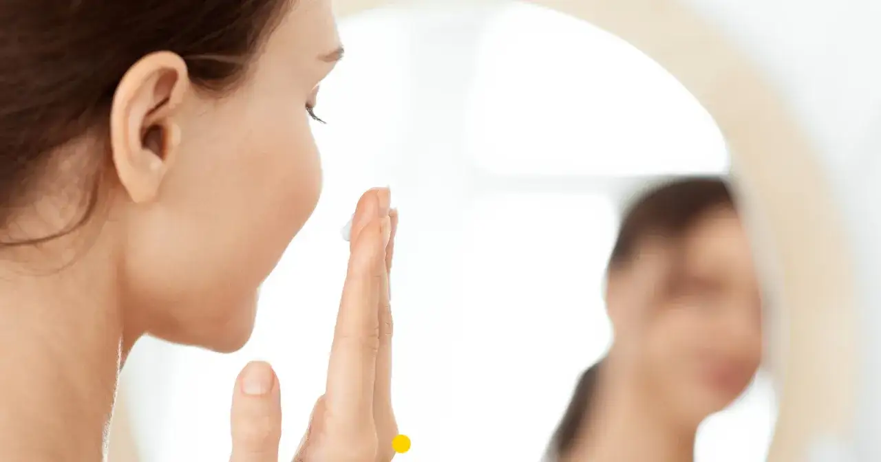 Kobieta nakłada krem na twarz, dbając o skórę. Czy wiesz, co to jest kolagen i jak wpływa na jej wygląd?