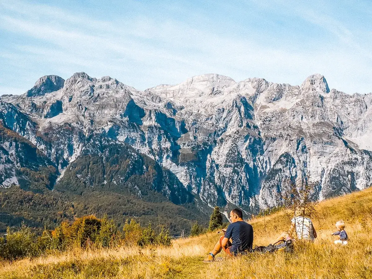 Rodzina odpoczywa na trawiastym zboczu, podziwiając majestatyczne albania góry.