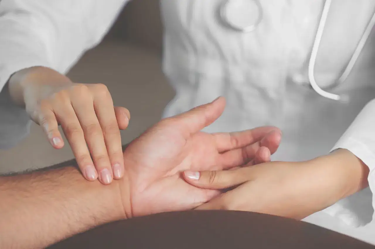 Lekarz bada puls pacjenta na nadgarstku.