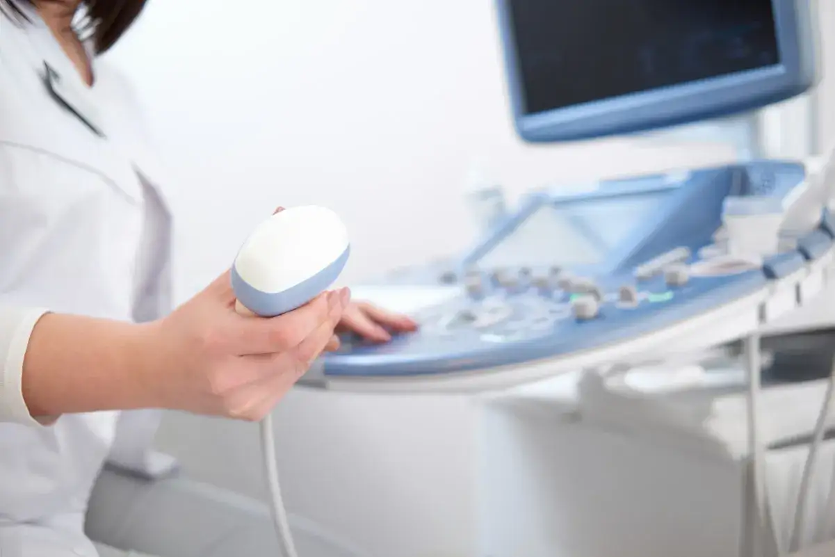 Lekarz trzyma sondę aparatu USG, przygotowując się do badania echo serca. Prawidłowe parametry echo serca są kluczowe dla diagnozy.