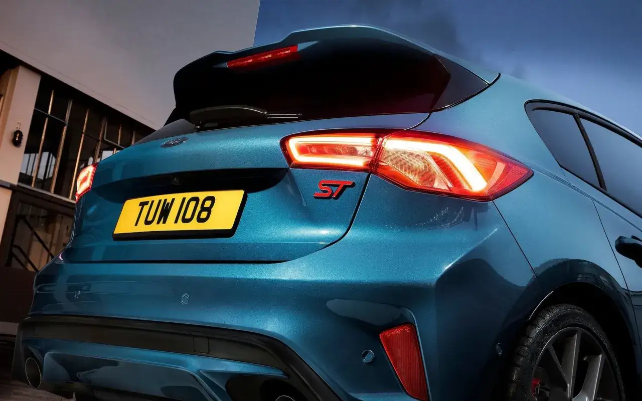 Tylna część sportowego Forda Focus ST 2025 w kolorze niebieskim, z podświetlonymi światłami i czerwonym emblematem ST.