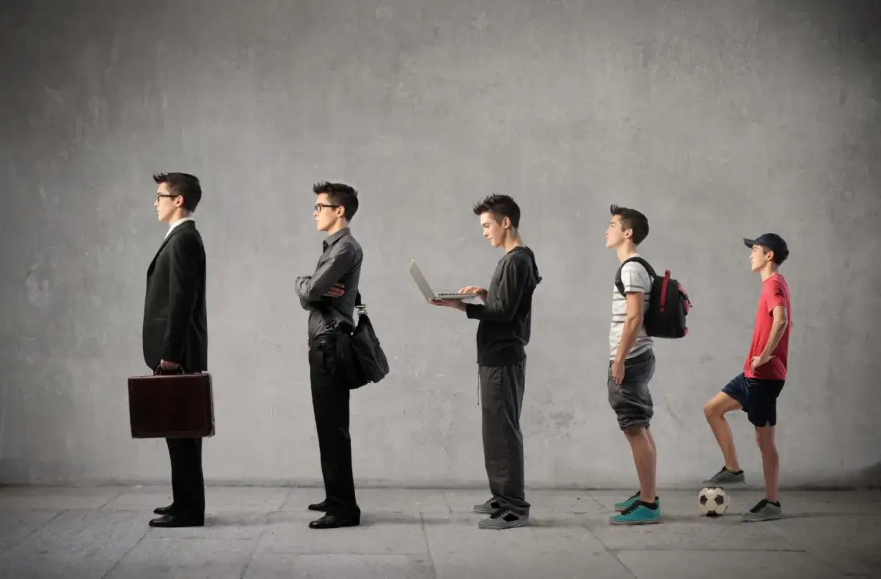 Kolejka młodych ludzi w różnym wieku, od biznesmena po chłopca z piłką, symbolizująca ścieżkę kariery i możliwości, jak oferty pracy w szkole.