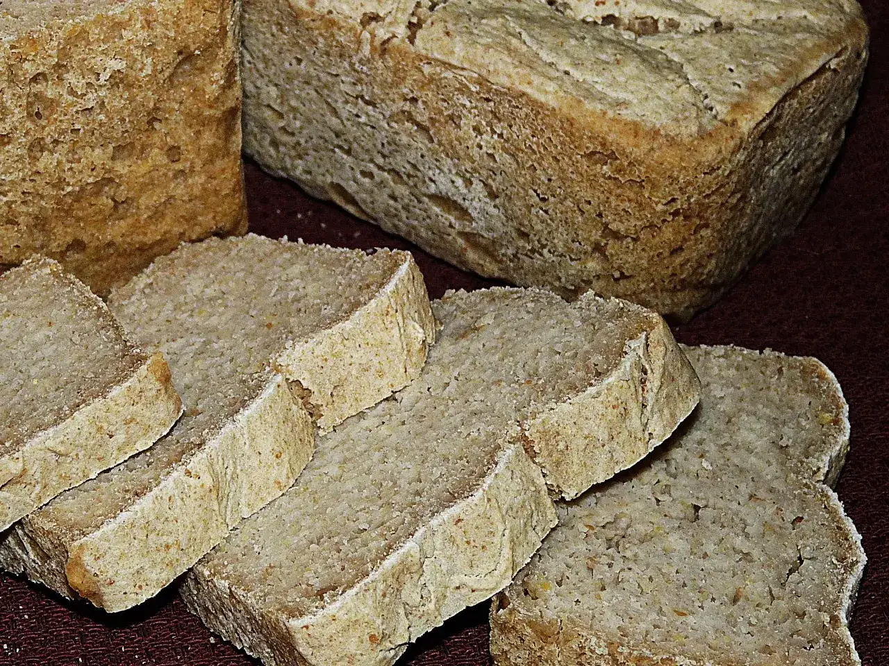 Chleb ryżowy bezglutenowy przepis. Pokrojone kromki domowego chleba ryżowego bezglutenowego na ciemnym tle.