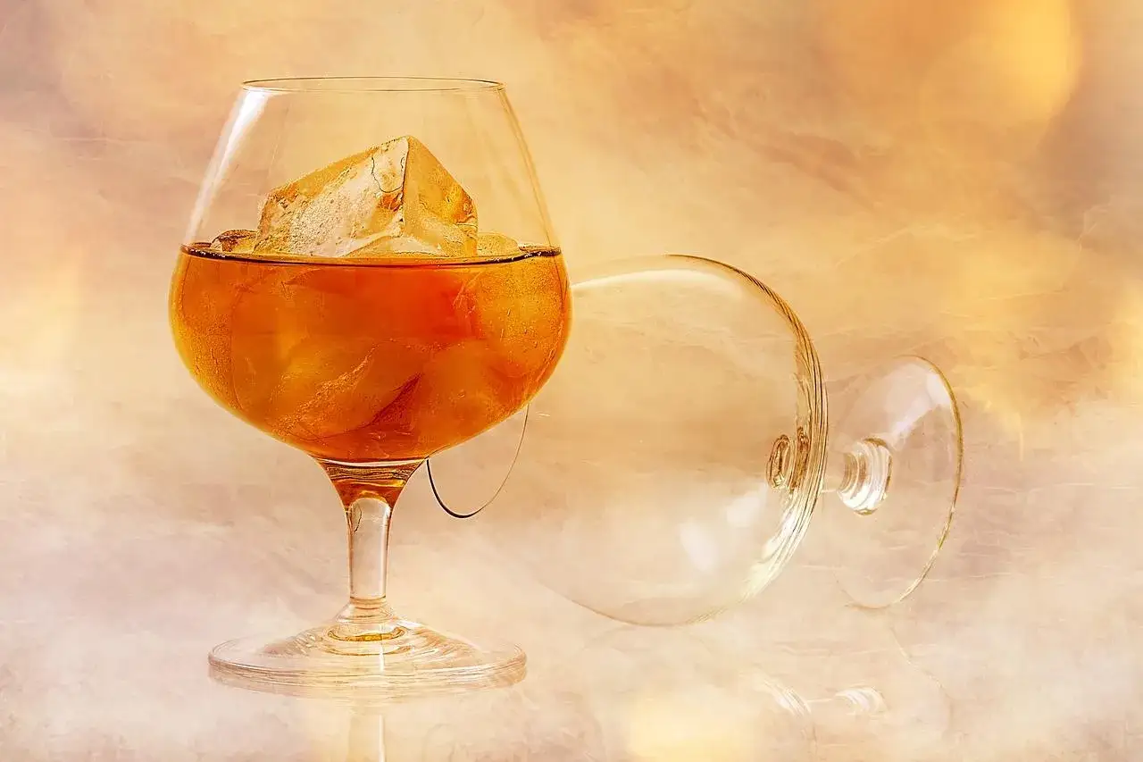 Kieliszek z brandy i lodem, obok pusty, przewrócony kieliszek. Idealny sposób, jak pić brandy.