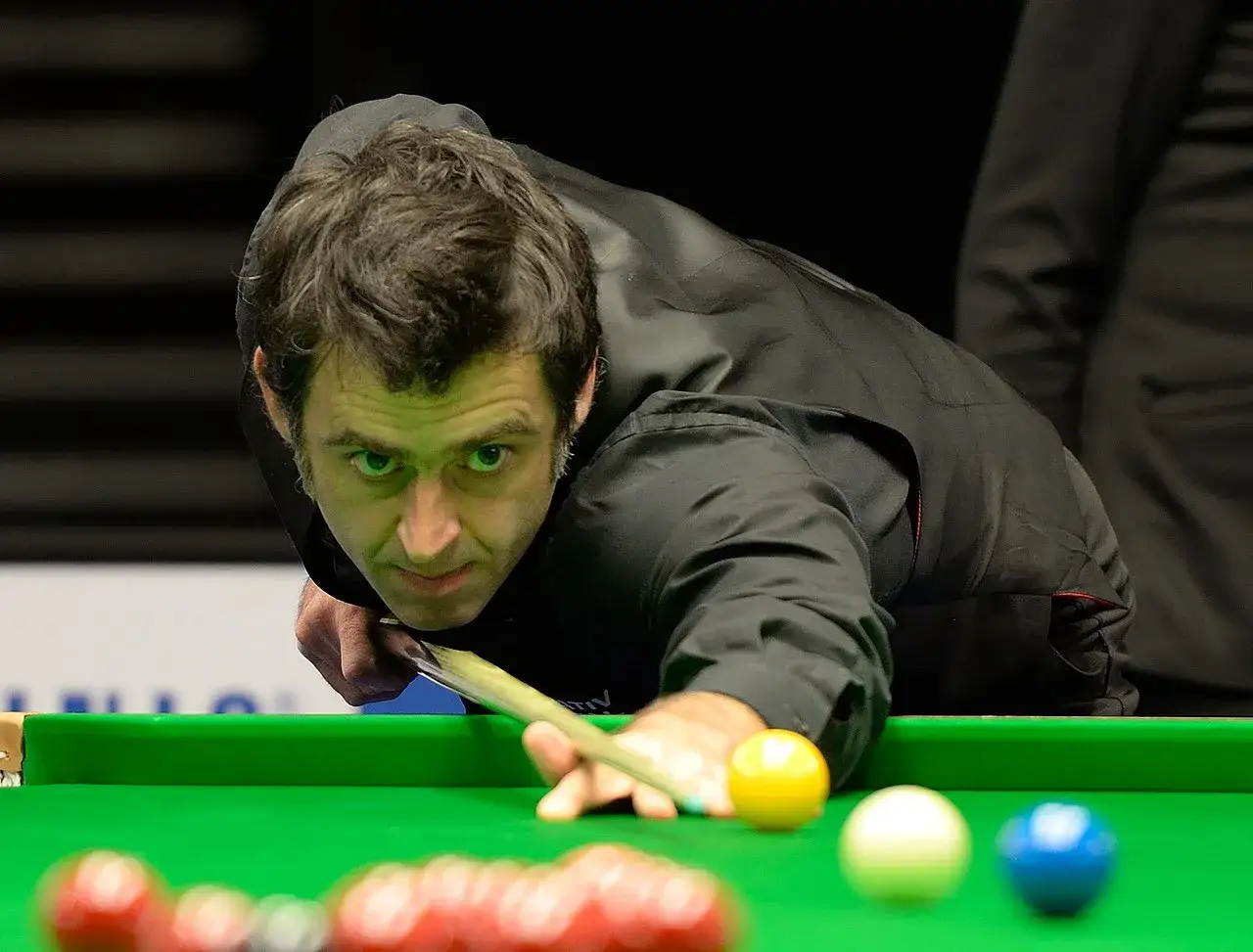 Ronnie O'Sullivan w akcji, skupiony na grze w snookera. Jego sportowa pasja widoczna w każdym ruchu.