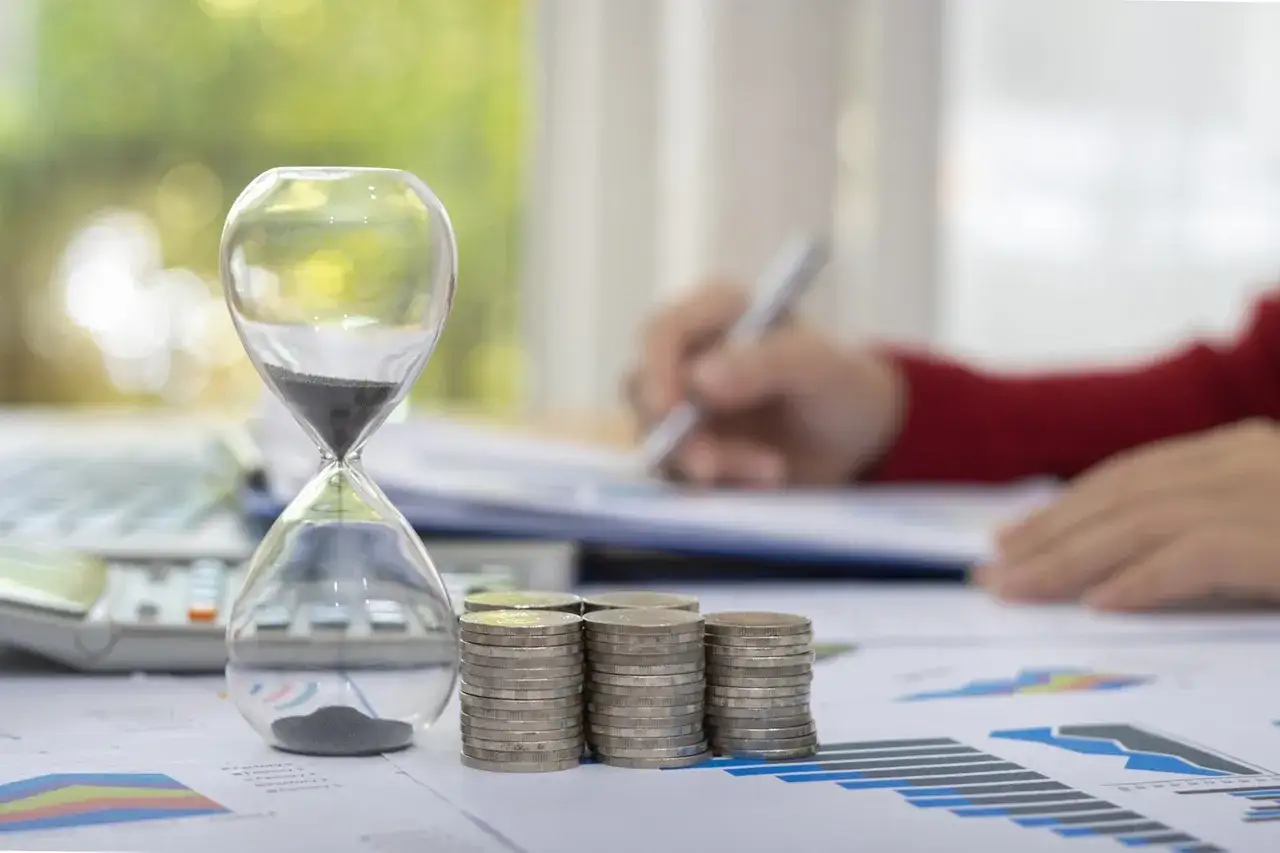 Klepsydra, monety i kalkulator symbolizują czas i finanse. Zastanawiasz się, na ile lat można wziąć kredyt gotówkowy?