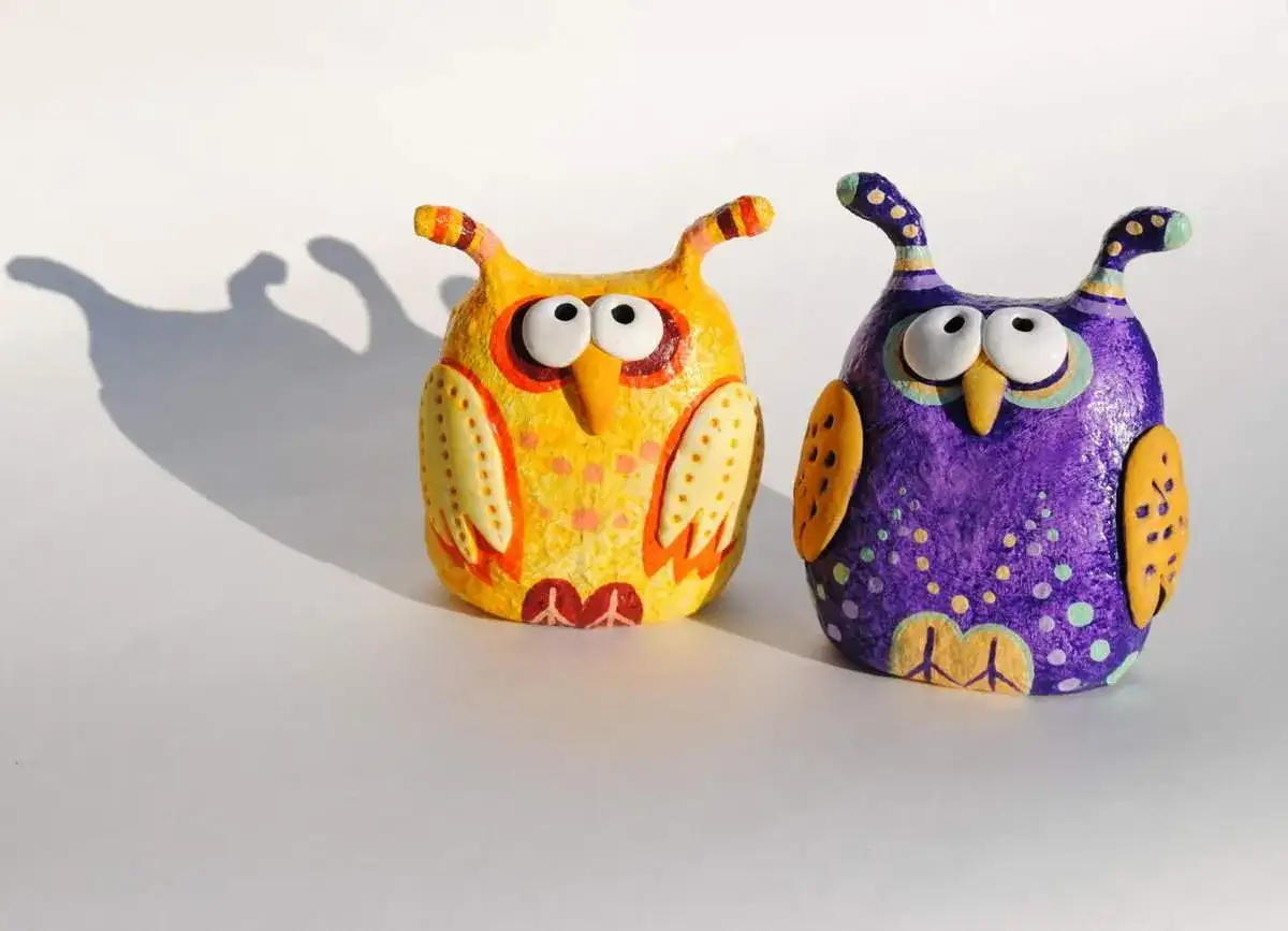 Dwa kolorowe sowy z gliny, żółta i fioletowa, ozdobione wzorami. Oto co można zrobić z gliny!