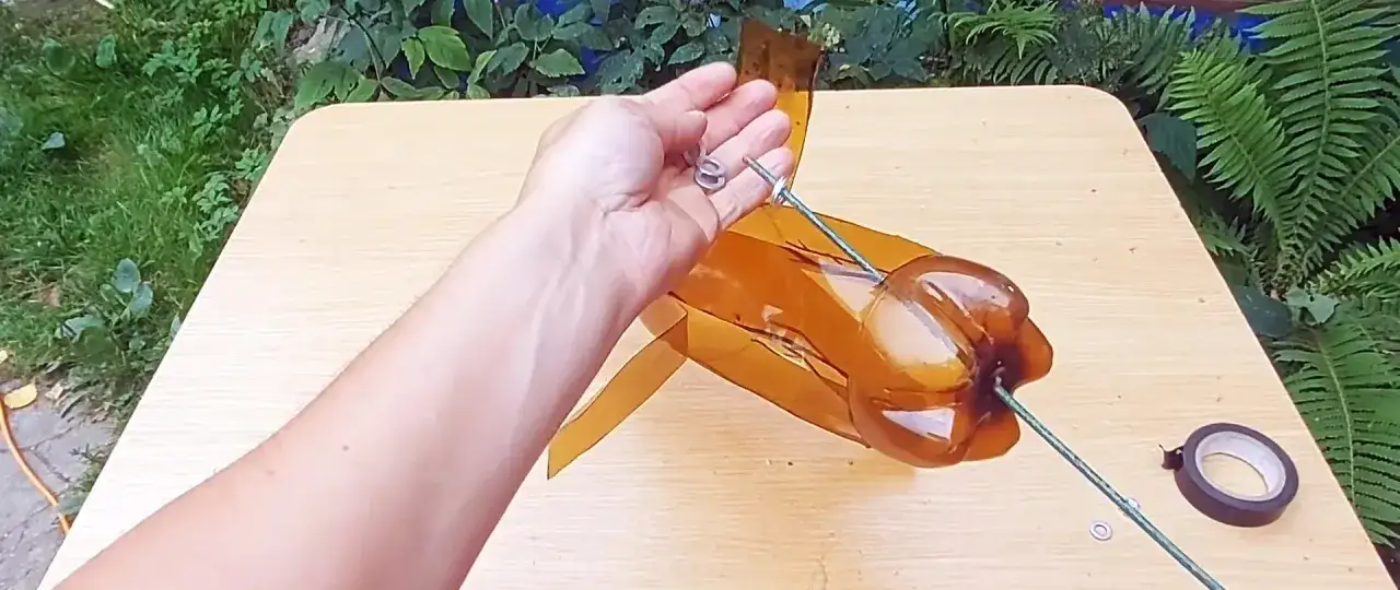 Ręka trzyma drut, który będzie częścią wiatraka z butelki. Widać przygotowane łopatki.