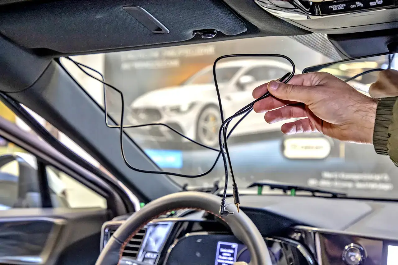 Mężczyzna trzyma kable, przygotowując się do tego, jak zamontować wideorejestrator w samochodzie.