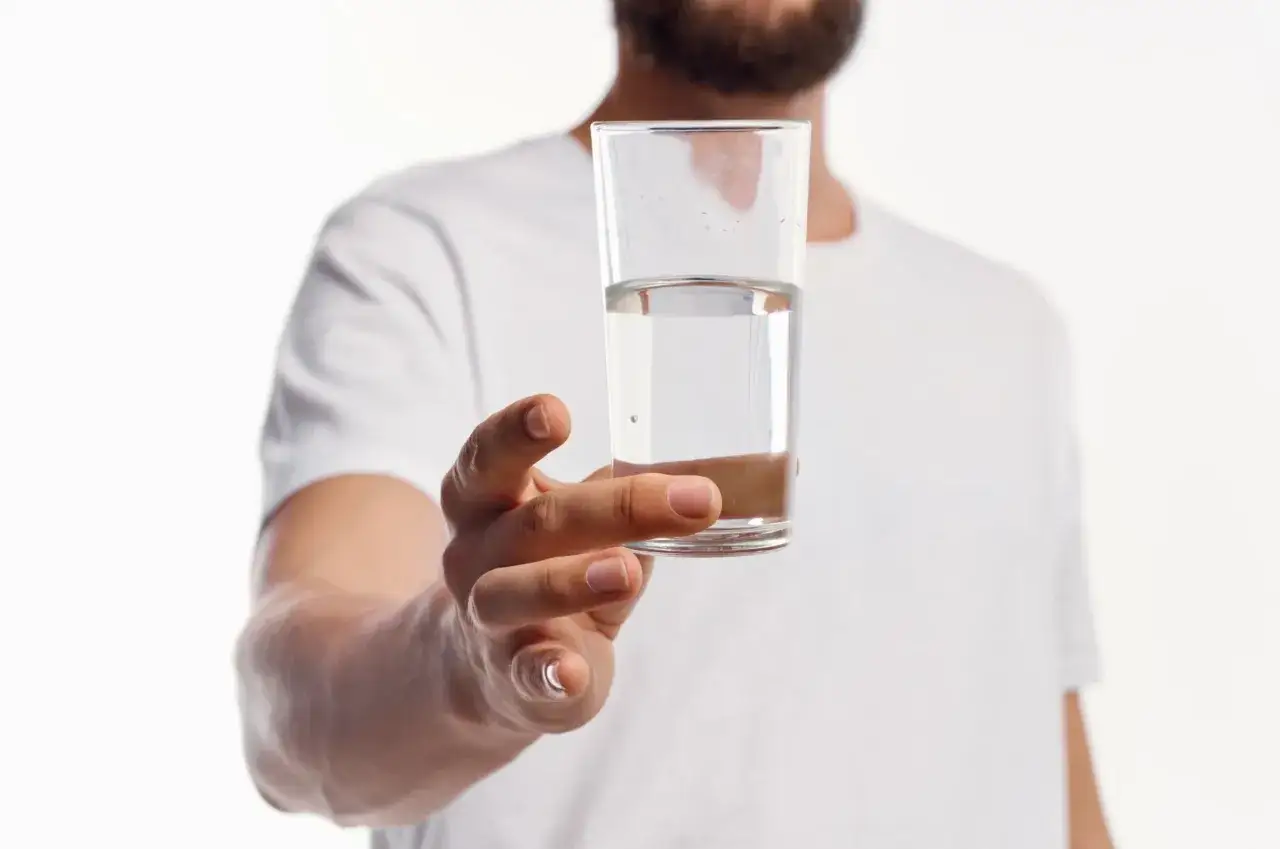 Mężczyzna trzyma szklankę z wodą. Zastanawiasz się, gdzie zbadać wodę z kranu?