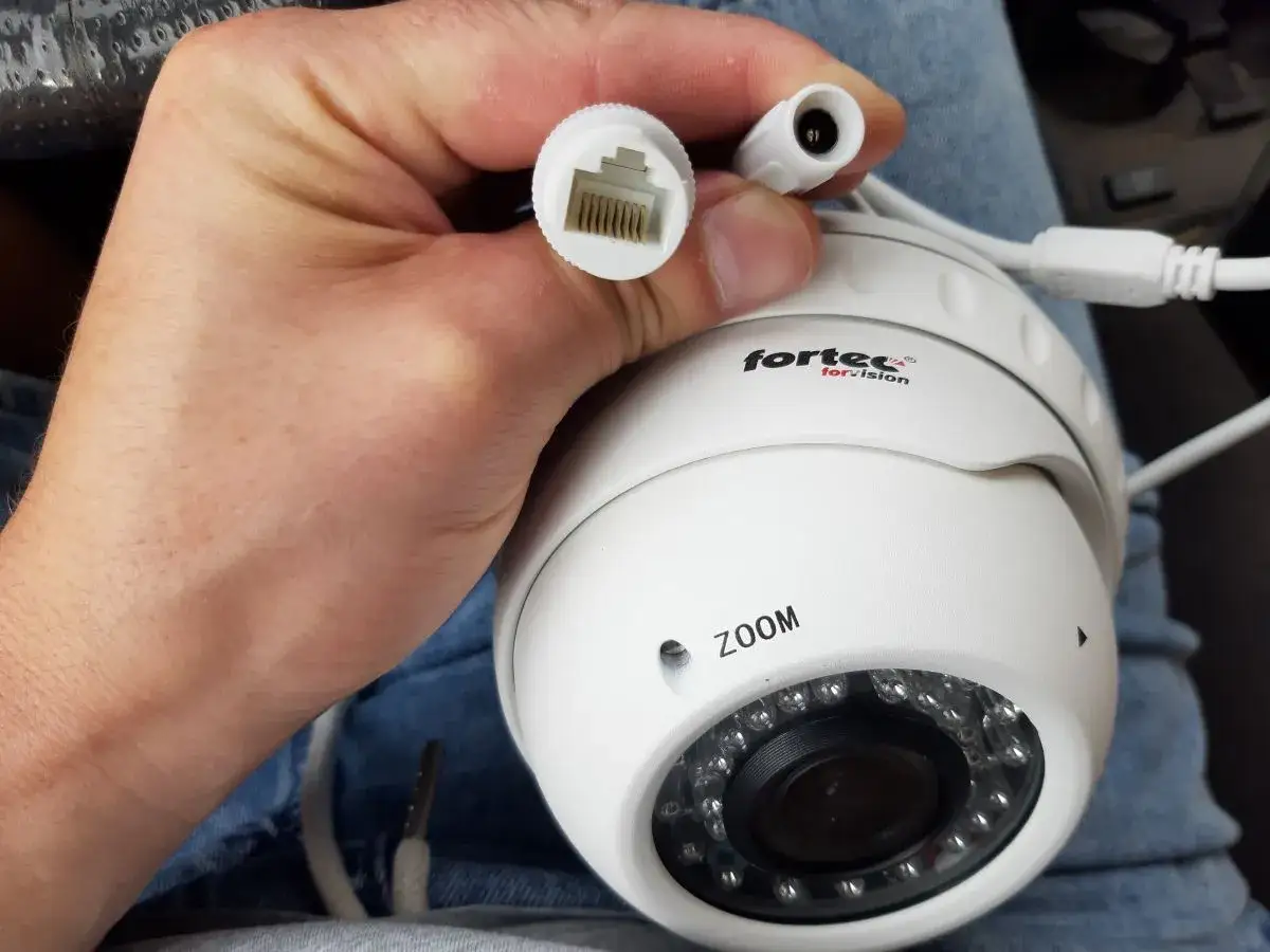 Dłoń trzyma białą kamerę IP z logo "fortec for vision". Widać złącze RJ45 i zasilania. Dowiedz się, jak podłączyć kamerę bez rejestratora.