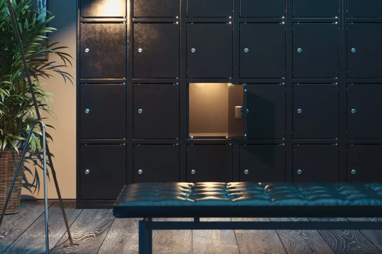 Rząd czarnych szafek, jedna otwarta, oświetlona od środka. Obok ławka i roślina. Kto to deponent?