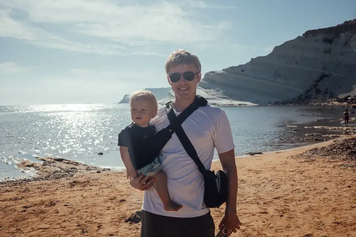 Ojciec z niemowlakiem na plaży, idealne miejsce, gdzie na wakacje z niemowlakiem. Słońce, morze i białe klify tworzą piękne tło.