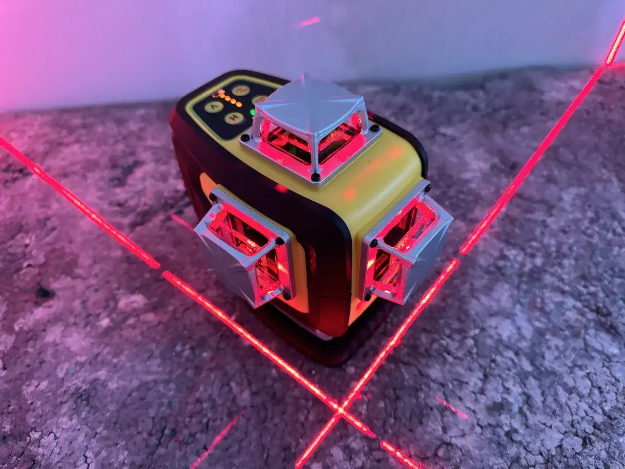 Poziomica laserowa z czerwonymi liniami laserowymi emitowanymi z kilku modułów.