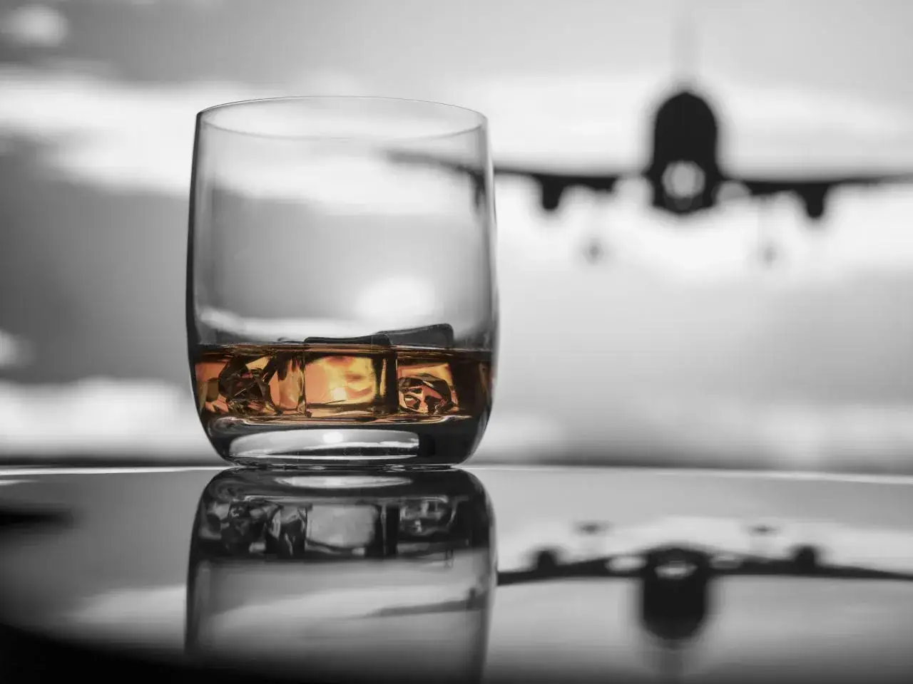 Szklanka whisky z lodem na tle samolotu. Czy można przewozić alkohol w samolocie Ryanair?