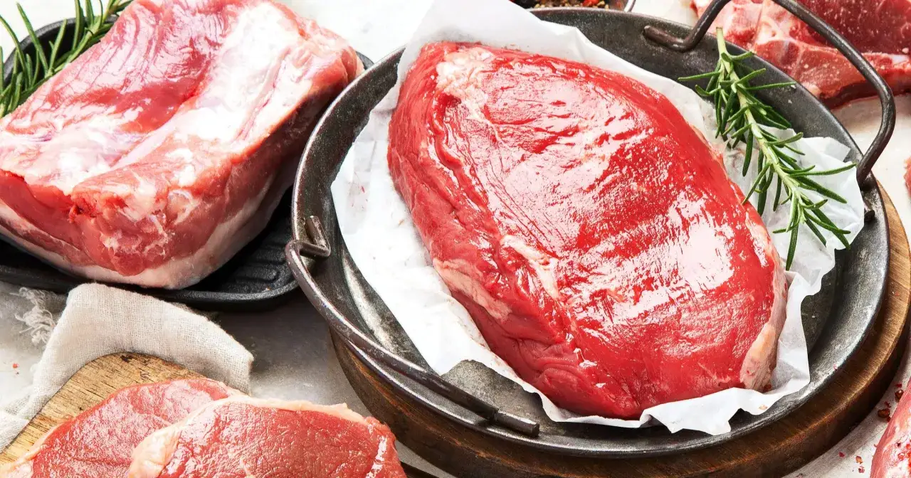 Surowe kawałki wołowiny i wieprzowiny z gałązkami rozmarynu.