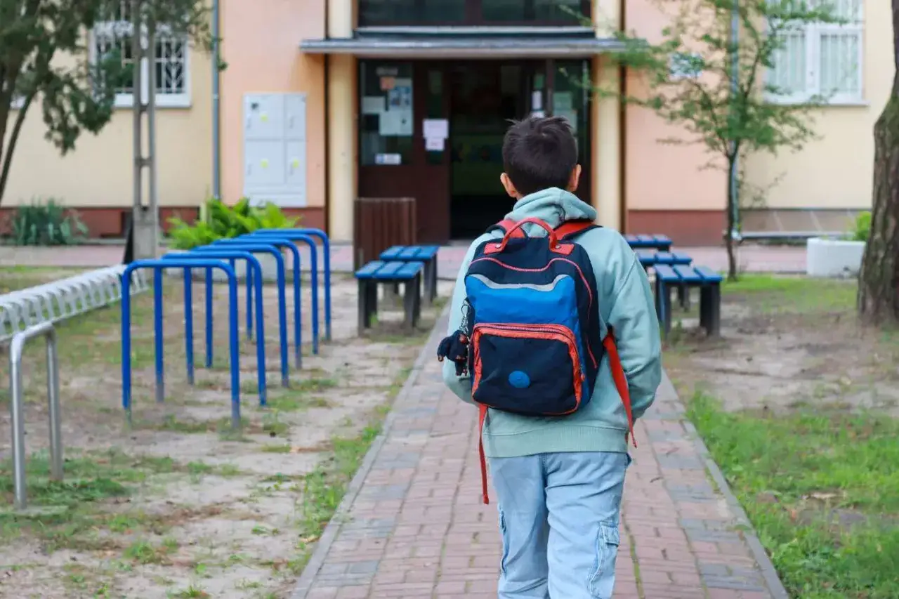 Chłopiec z plecakiem idzie do szkoły. Zastanawia się, czy religia liczy się do średniej.