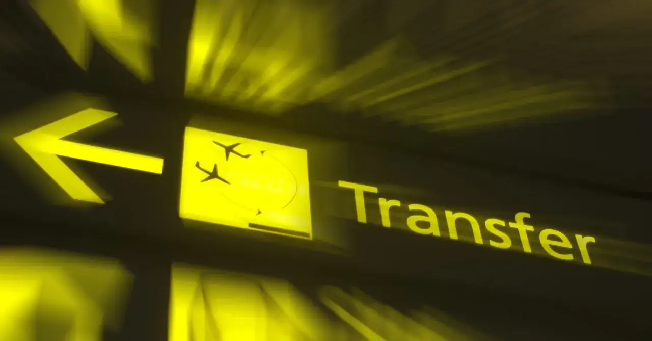 Żółty znak lotniskowy z ikoną samolotu i napisem "Transfer". Czy można opuścić lotnisko podczas przesiadki?