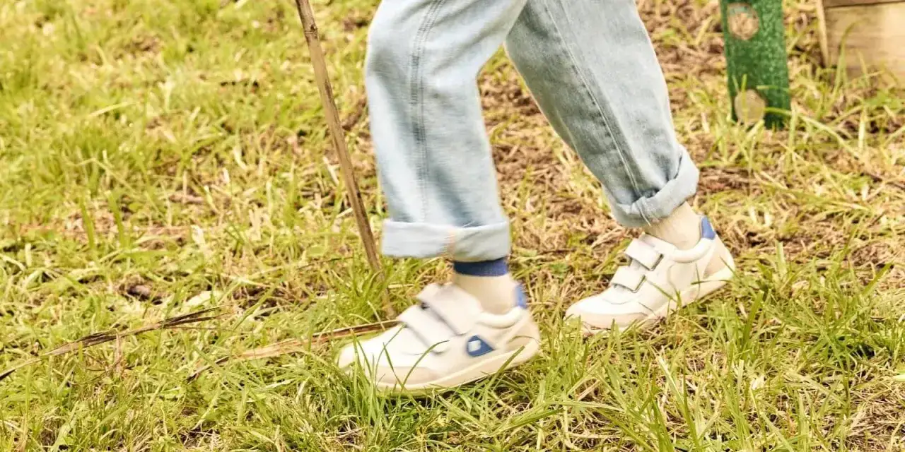 Białe sneakersy na rzepy, idealne na spacer po trawie. To wygodne buty dla aktywnych.