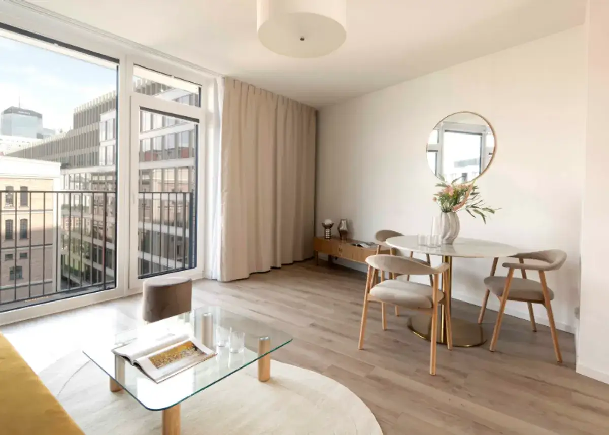 Nowoczesne mieszkanie inwestycyjne co to znaczy? Jasny salon z jadalnią, balkonem i widokiem na miasto.