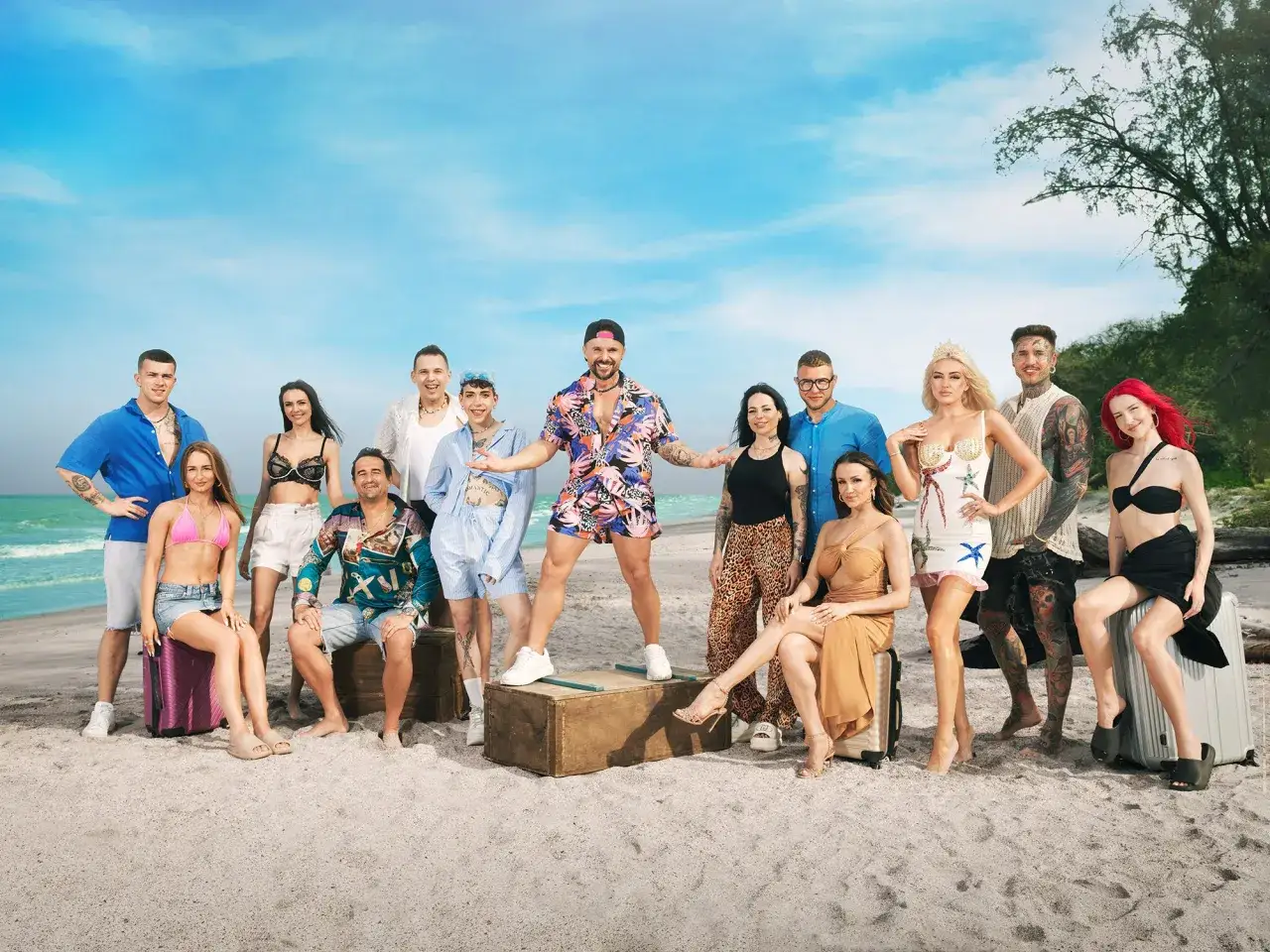 Grupa młodych ludzi na plaży, gotowa na przygodę. Trzymają walizki, a ich stroje sugerują wakacyjny klimat. good luck guys!