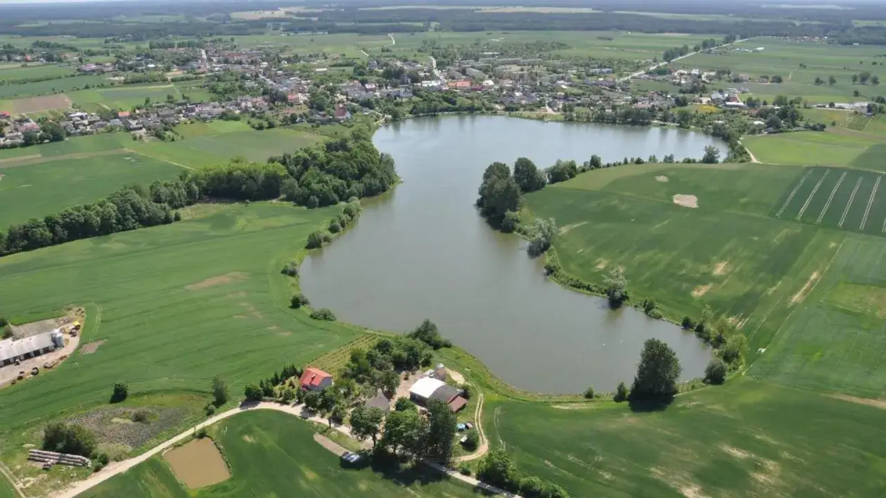 Widok z lotu ptaka na jezioro, pola uprawne i zabudowania w Przechlewie.