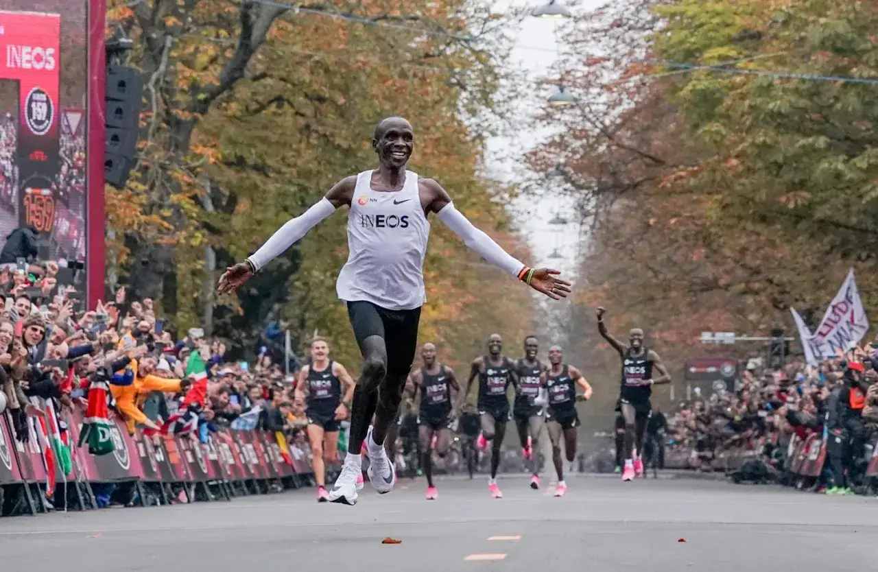 Eliud Kipchoge przekracza linię mety, ustanawiając nowy maraton rekord świata. Tłumy wiwatują, widząc historyczny bieg.