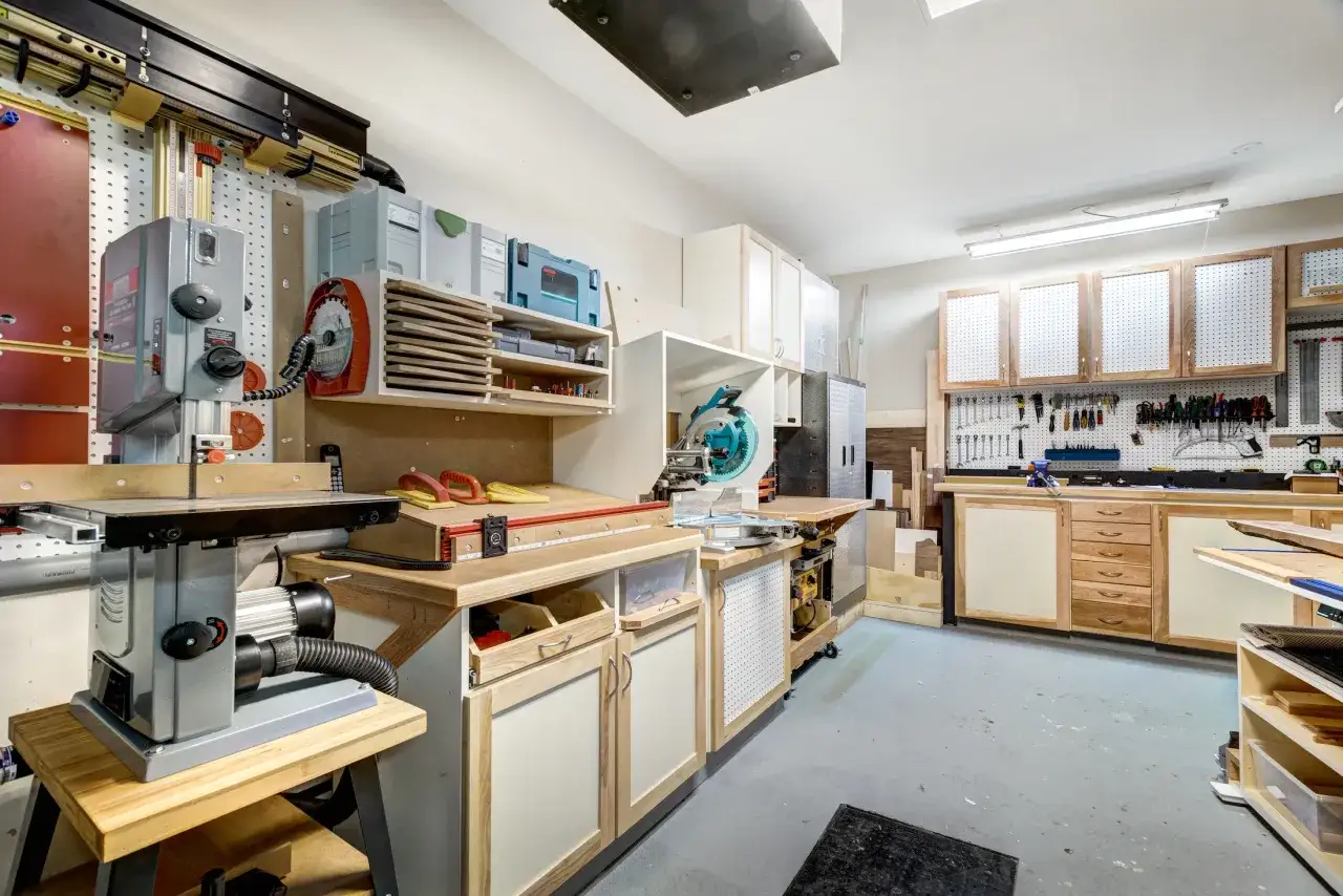 Warsztat stolarski z piłą taśmową, stołem i szafkami.