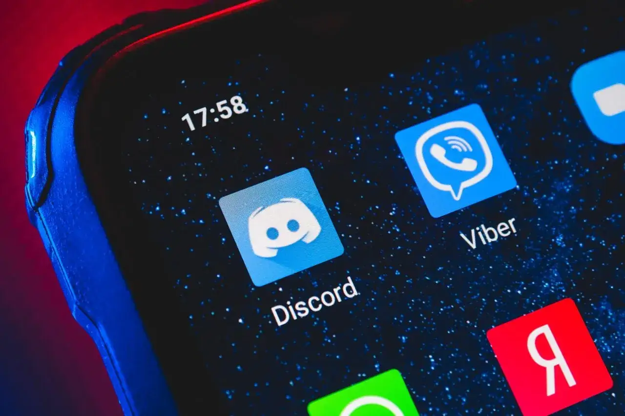 Ikona Discord na ekranie telefonu. Dowiedz się, jak dodać bota do Discorda, aby ulepszyć swój serwer.
