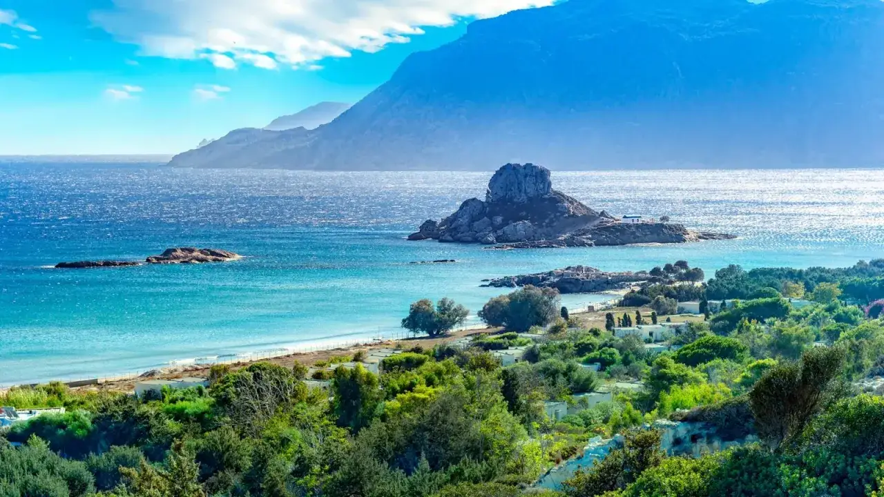 Widok na turkusowe morze, skaliste wysepki i zielone wzgórza na greckiej wyspie Kos.