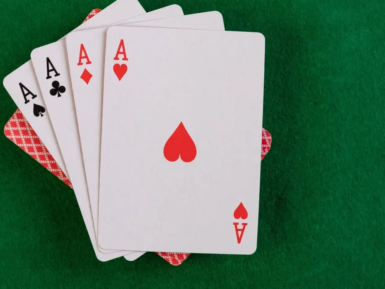 Cztery asy kart do gry na zielonym tle.