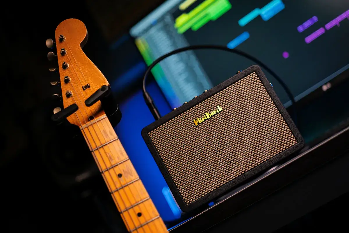 Gitara elektryczna i mały wzmacniacz z napisem "Minibomb". Pytanie: czy do gitary elektrycznej można podłączyć słuchawki? Odpowiedź: tak, często można.