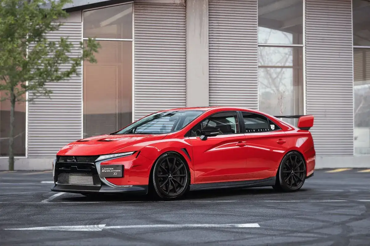 Czerwony Mitsubishi Lancer Evolution XI z czarnymi felgami i spoilerem, zaparkowany przed nowoczesnym budynkiem.