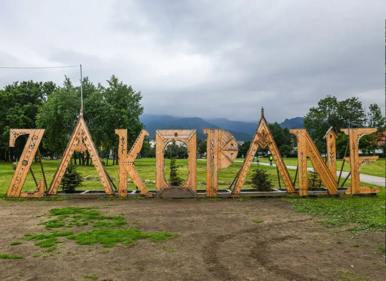 Drewniany napis "ZAKOPANE" na tle gór. Idealne miejsce na rozpoczęcie poszukiwań zakopane atrakcje dla dorosłych.